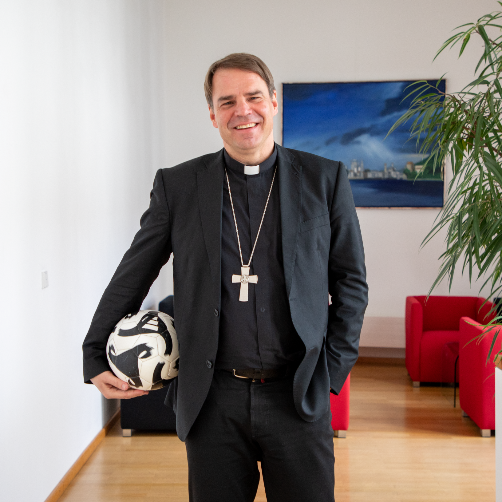 Bild des Sportbischofs der DBK, Bischof Stefan Oster, mit Fußball unterm Arm